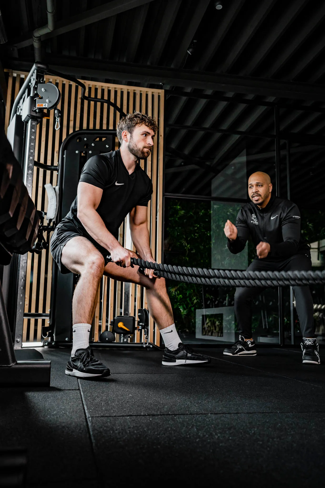 Coach begeleidt één klant met battle ropes